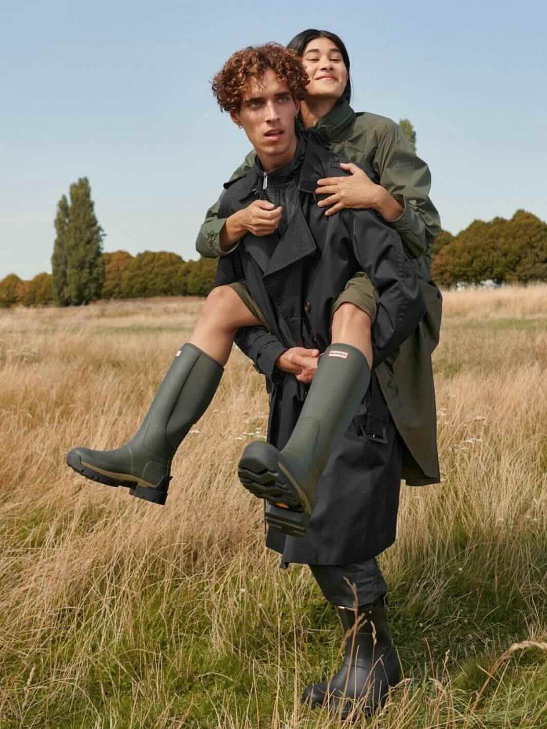 Et par menn og en kvinne med Hunter-støvler av typen Original Tall Boot og Balmoral i et skogsområde.