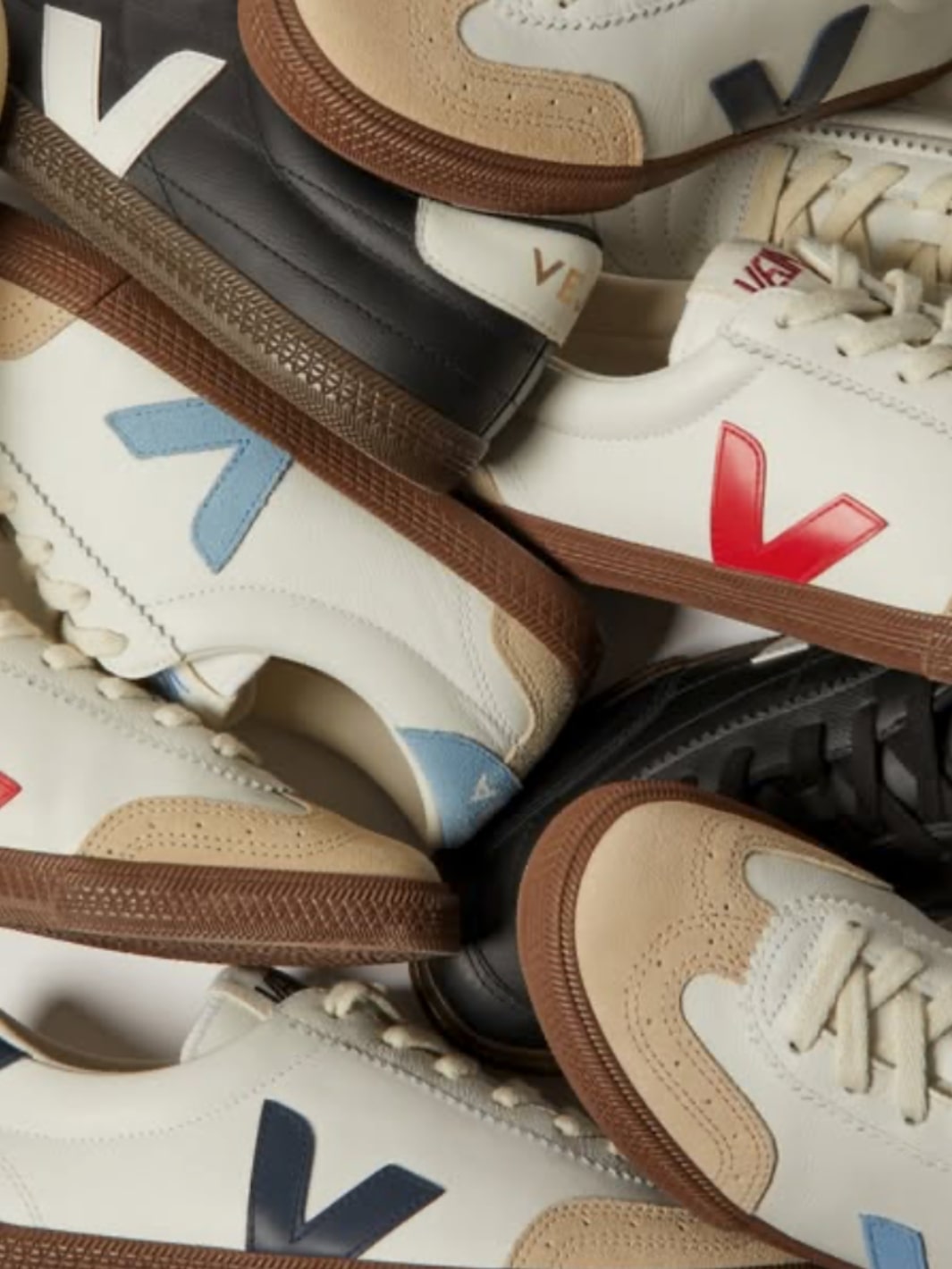 Utsnittsbilde av sneakers fra Veja som ligger lagvis over hverandre hvor Veja-logoen i ulike farger kommer tydelig frem.